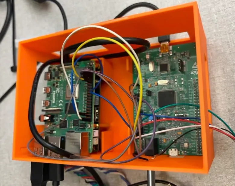 Enclosure internal view. The Raspberry Pi is nestled with the STM32 inside an orange enclosure